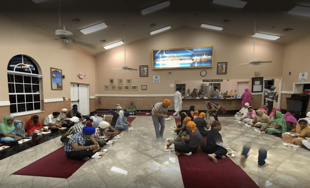 Sangat seated together sharing Guru Ka Langar, the free community meal, in the Langar hall